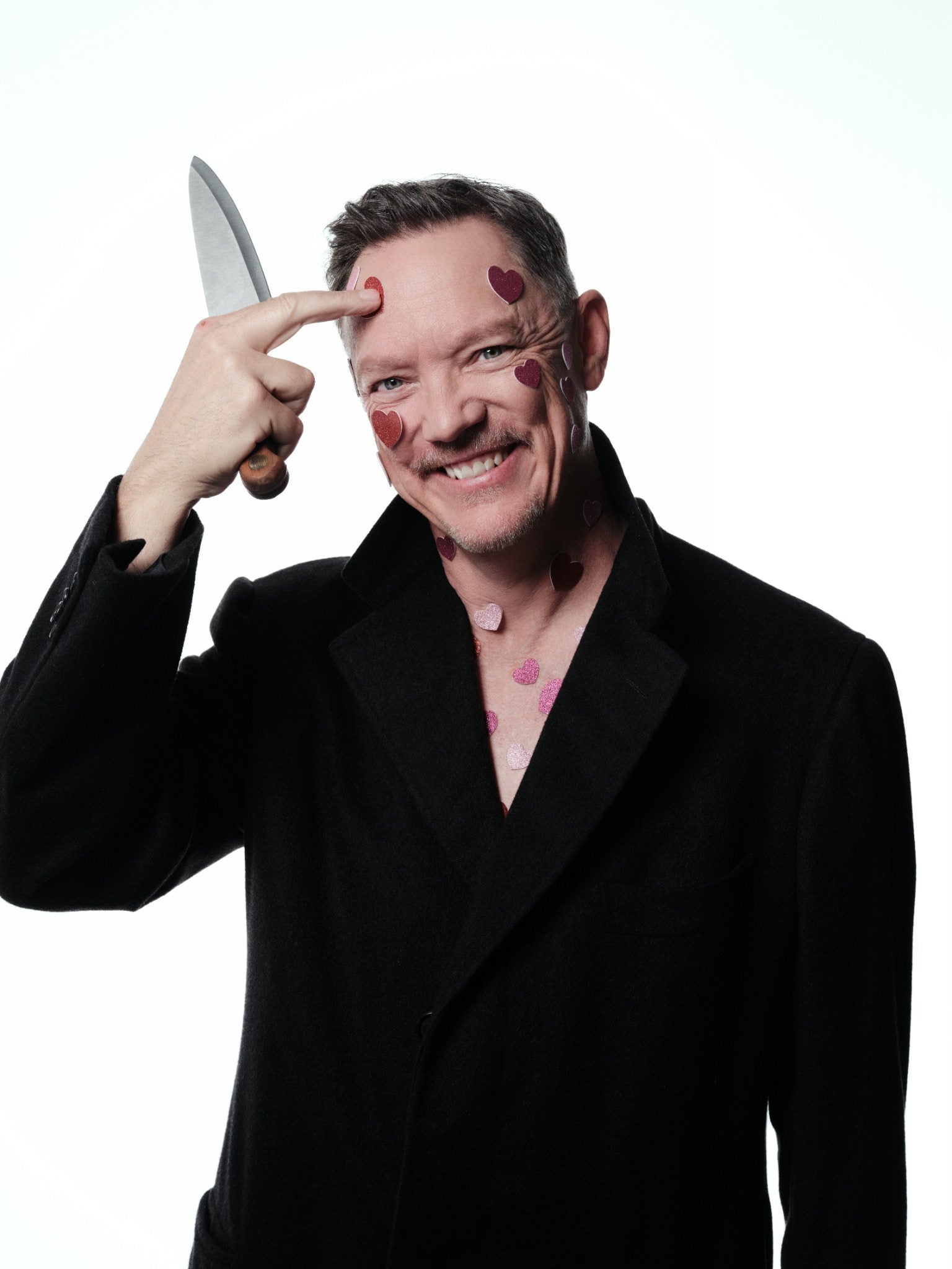 Matthew Lillard photographed with a theatrical prop knife and heart motifs