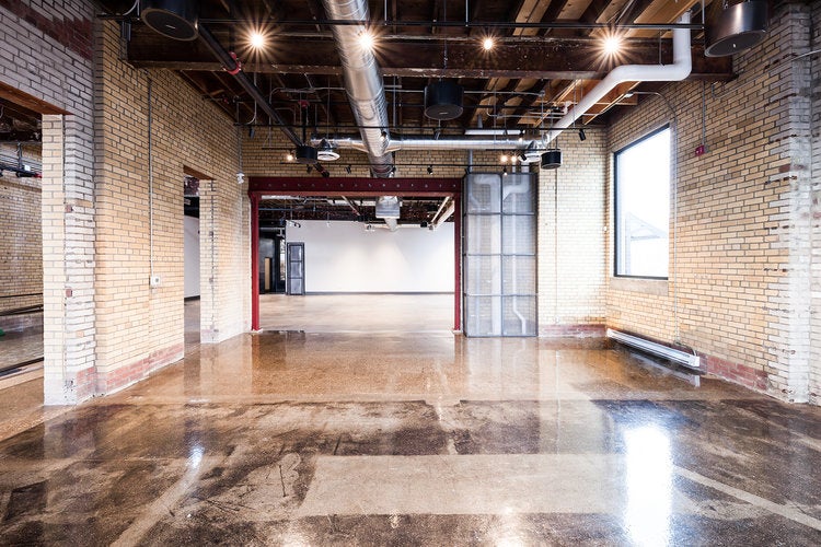 large event space with polished floors, brick walls, beams